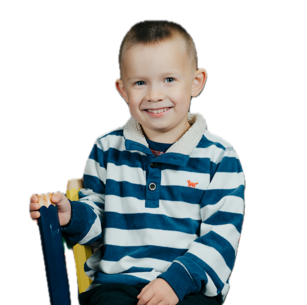 kinder boy sitting on school chair in striped shirt smiling at the camera